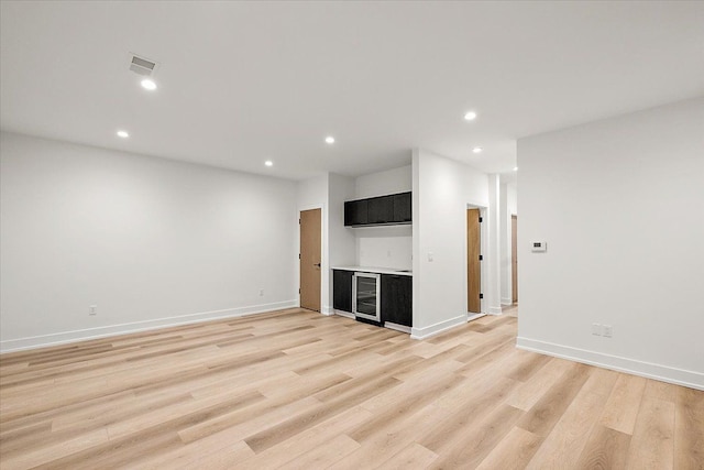 unfurnished living room featuring light wood-type flooring and beverage cooler