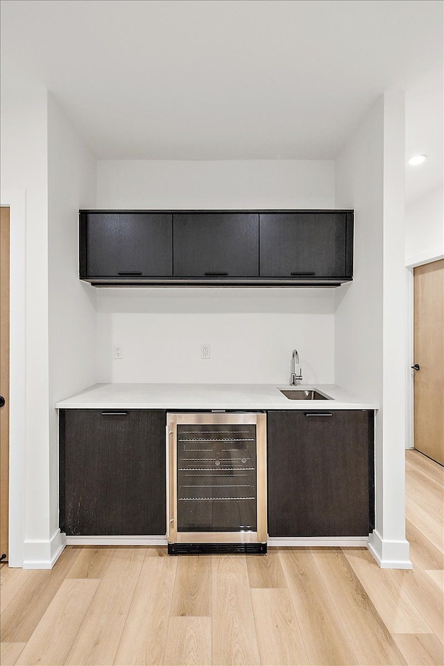 bar featuring wine cooler, sink, and light hardwood / wood-style floors