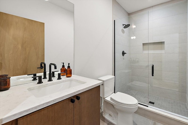 bathroom with tile patterned floors, vanity, toilet, and a shower with shower door