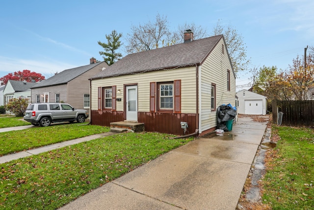 bungalow-style house featuring a front yard, a garage, and an outdoor structure