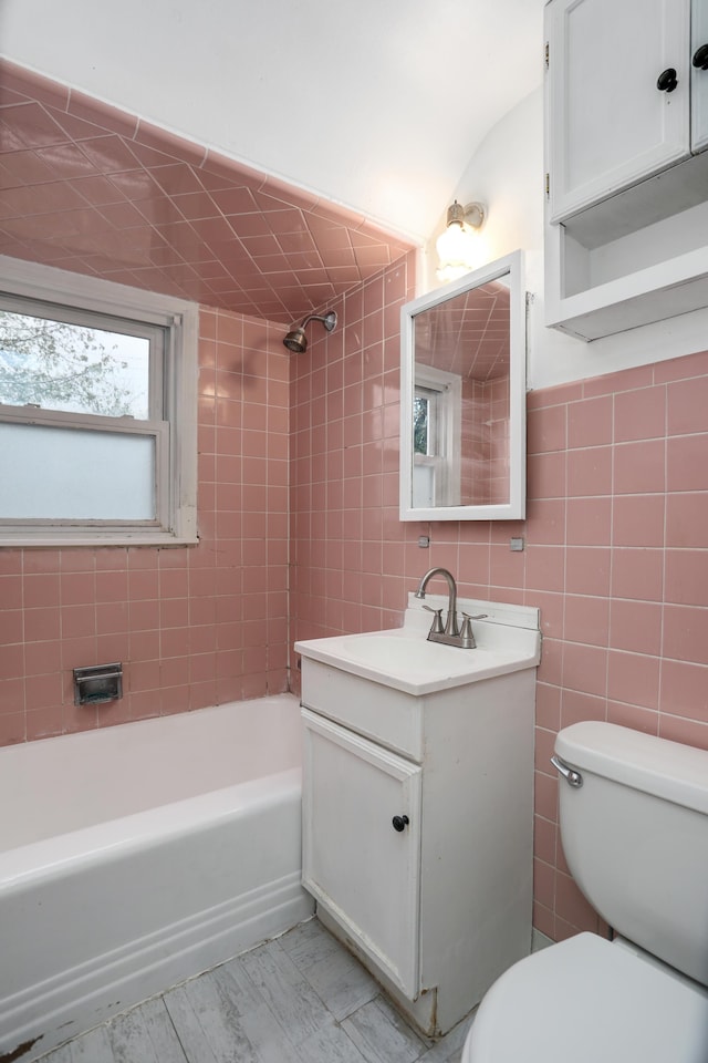 full bathroom featuring lofted ceiling, toilet, vanity, tile walls, and tiled shower / bath