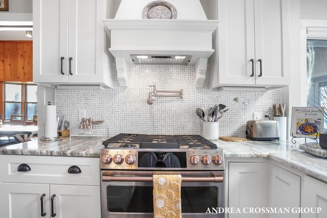 1155 Edgewater Ter, South Haven, MI 49090 - kitchen with stainless steel gas stove, premium range hood, tasteful backsplash, white cabinetry, and light stone counters