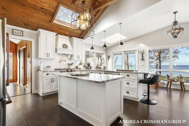 1155 Edgewater Ter, South Haven, MI 49090 - kitchen with a skylight, a peninsula, premium range hood, a chandelier, and high vaulted ceiling