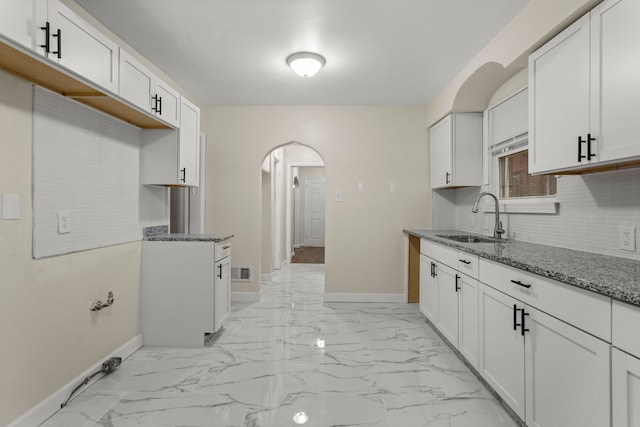 kitchen featuring decorative backsplash, white cabinetry, sink, and stone counters