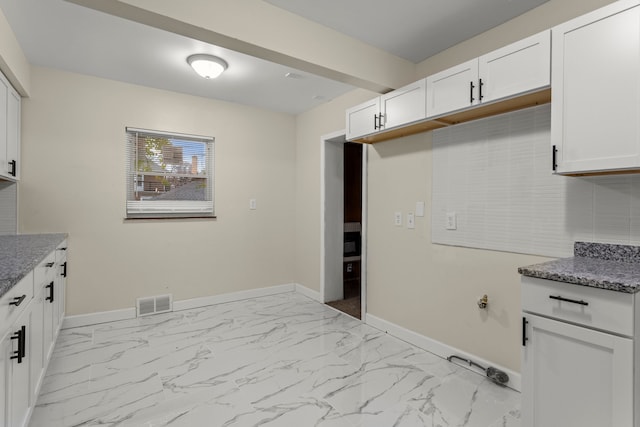 kitchen with dark stone countertops and white cabinets