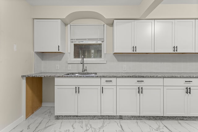 kitchen with light stone counters, white cabinetry, sink, and tasteful backsplash