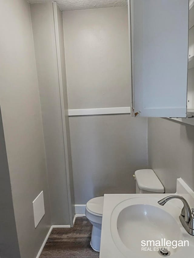 bathroom featuring a textured ceiling, toilet, wood-type flooring, and sink