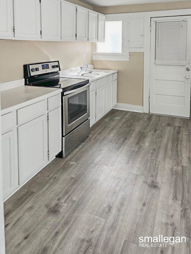 kitchen featuring hardwood / wood-style floors, sink, white cabinetry, and stainless steel range with electric cooktop