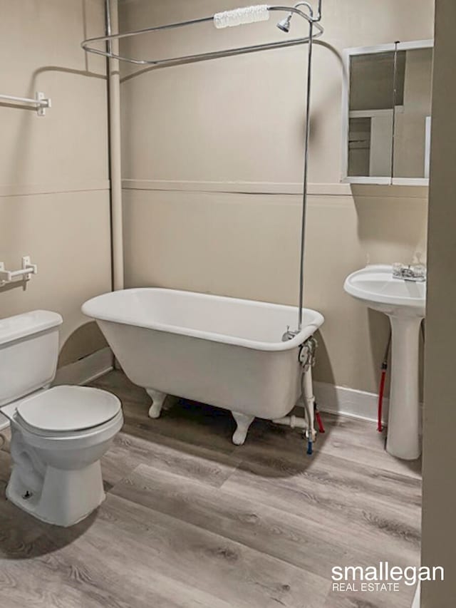 bathroom with hardwood / wood-style floors, toilet, and a bathing tub