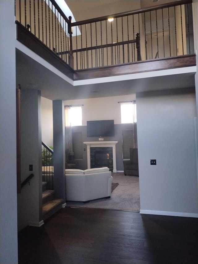 living room with plenty of natural light, a towering ceiling, and hardwood / wood-style floors