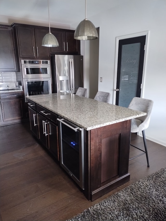 kitchen featuring a center island, wine cooler, light stone counters, dark brown cabinets, and appliances with stainless steel finishes