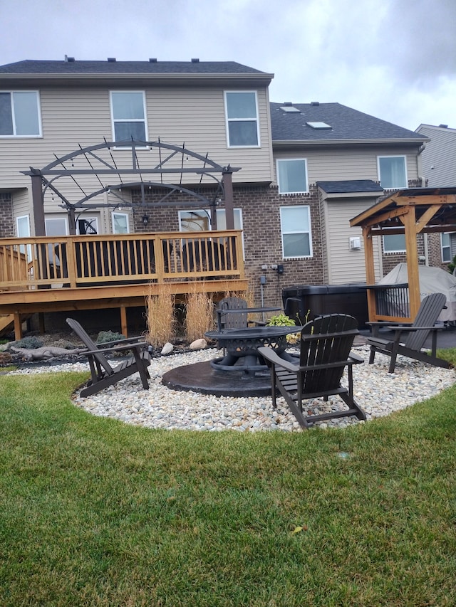 rear view of house with a yard, a pergola, a fire pit, and a wooden deck