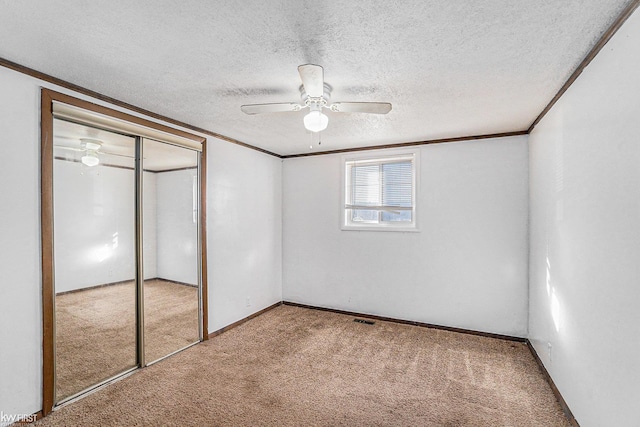 470 Michelson Rd, Houghton Lake, MI 48629 - unfurnished bedroom featuring carpet floors, ornamental molding, a textured ceiling, a closet, and a ceiling fan