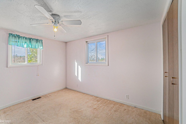 470 Michelson Rd, Houghton Lake, MI 48629 - unfurnished bedroom featuring a textured ceiling, multiple windows, baseboards, and light carpet