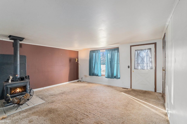 foyer entrance with a wood stove, carpet floors, and ornamental molding