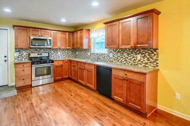 kitchen featuring backsplash, sink, light hardwood / wood-style flooring, and appliances with stainless steel finishes