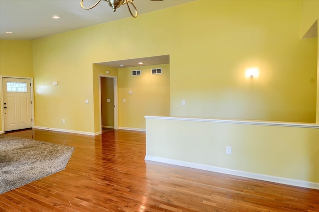 interior space featuring a towering ceiling, hardwood / wood-style flooring, and a notable chandelier