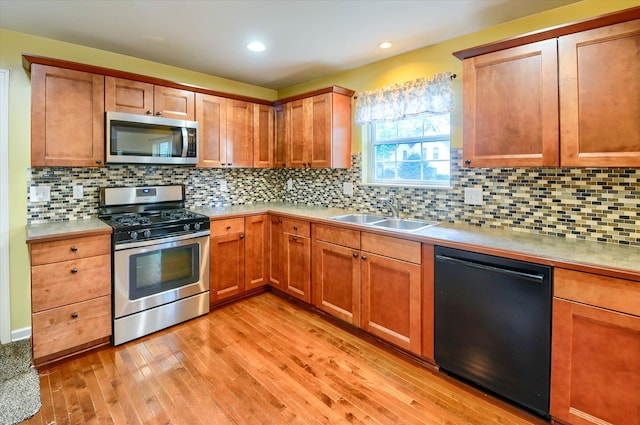 kitchen featuring appliances with stainless steel finishes, light wood-type flooring, backsplash, and sink