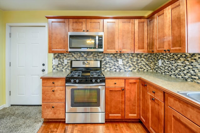 kitchen featuring appliances with stainless steel finishes, backsplash, and light hardwood / wood-style floors