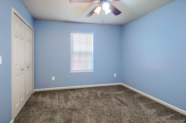 unfurnished bedroom featuring ceiling fan, a closet, and dark carpet