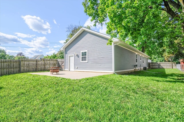 back of property with a lawn, a fire pit, and a patio