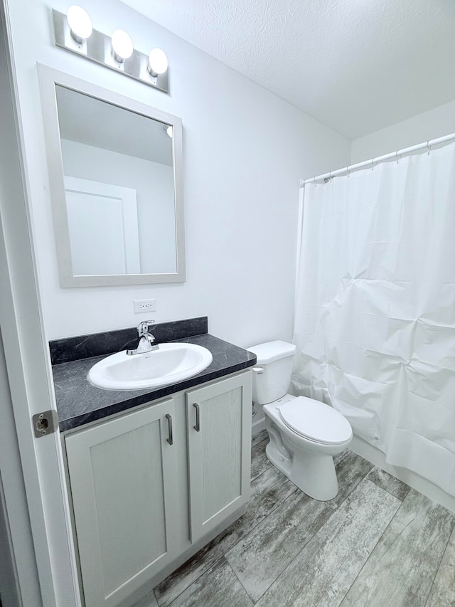 bathroom featuring hardwood / wood-style floors, vanity, a textured ceiling, and toilet