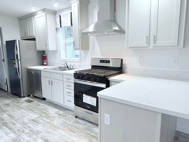 kitchen featuring white cabinets, light hardwood / wood-style flooring, wall chimney exhaust hood, and appliances with stainless steel finishes