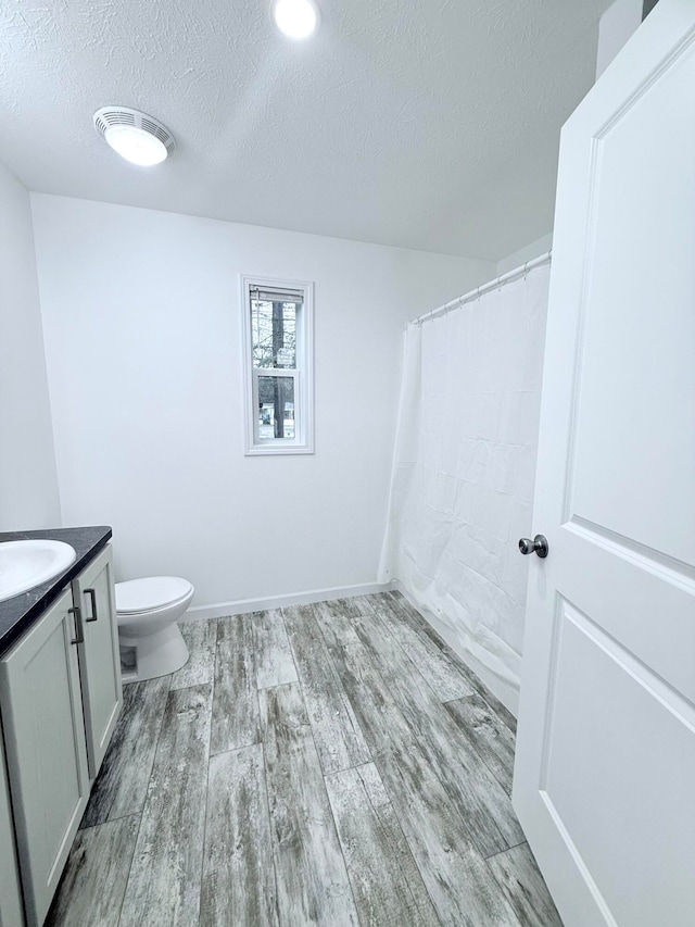 bathroom featuring vanity, toilet, wood-type flooring, and a textured ceiling