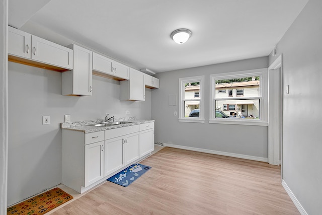 kitchen featuring white cabinets, light hardwood / wood-style floors, light stone countertops, and sink