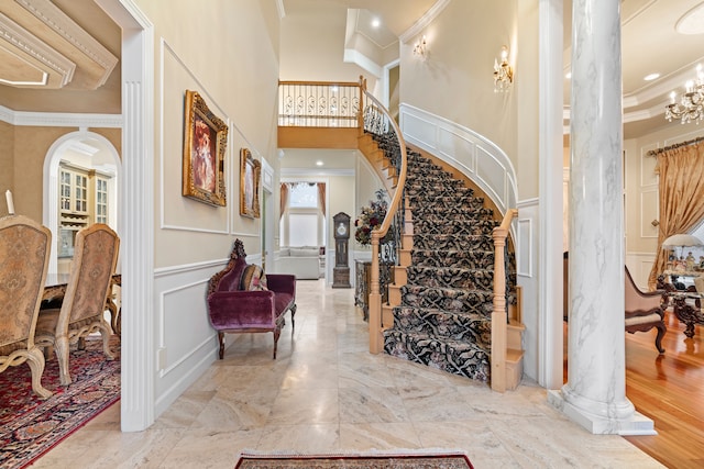 stairs with arched walkways, wainscoting, crown molding, and a decorative wall