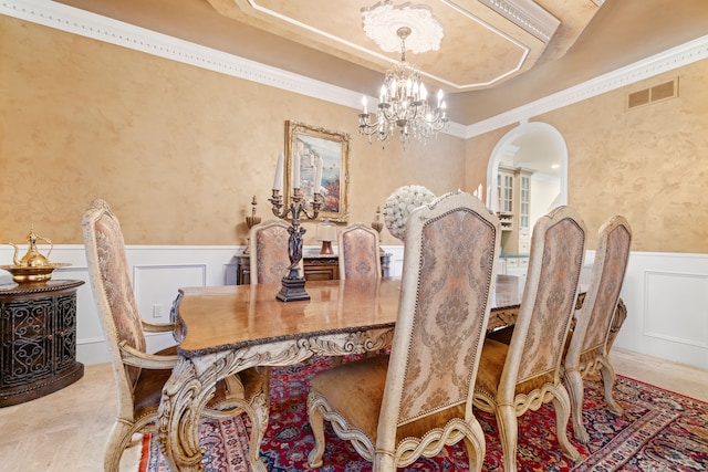 dining space featuring visible vents, arched walkways, wainscoting, a decorative wall, and a chandelier