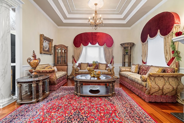 living room featuring a tray ceiling, a notable chandelier, wood finished floors, and wainscoting