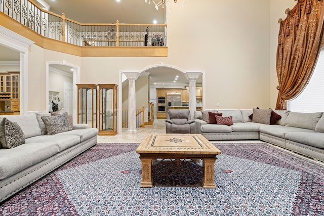 living room with a high ceiling, arched walkways, ornate columns, and ornamental molding