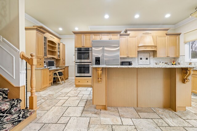 kitchen with ornamental molding, light brown cabinetry, custom range hood, appliances with stainless steel finishes, and decorative backsplash