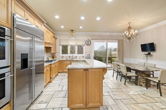 kitchen with ornamental molding, a kitchen island, stone tile floors, stainless steel appliances, and light stone countertops