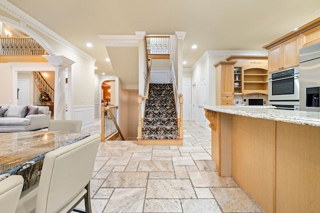 kitchen with stone tile flooring, recessed lighting, arched walkways, light stone countertops, and ornate columns