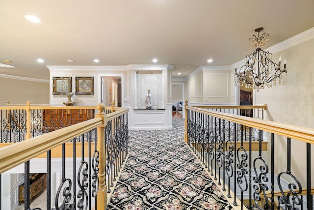 corridor with carpet floors, an upstairs landing, ornamental molding, a notable chandelier, and a decorative wall