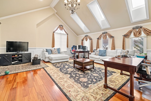 living room with a wainscoted wall, wood finished floors, an inviting chandelier, a skylight, and crown molding