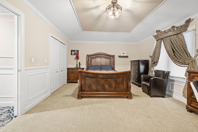 bedroom with a wainscoted wall, light carpet, a closet, and crown molding