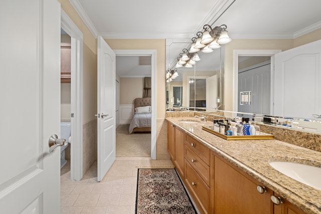 ensuite bathroom featuring a sink, double vanity, tile patterned floors, and ornamental molding