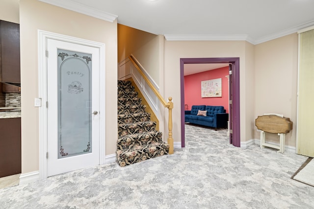 foyer entrance with crown molding, stairs, baseboards, and carpet floors