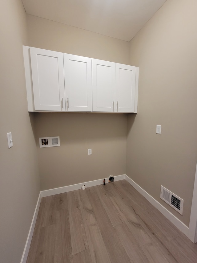 washroom with hookup for a gas dryer, hookup for a washing machine, cabinets, and light hardwood / wood-style floors