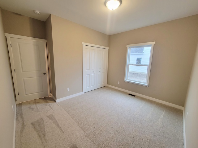 unfurnished bedroom featuring light carpet and a closet