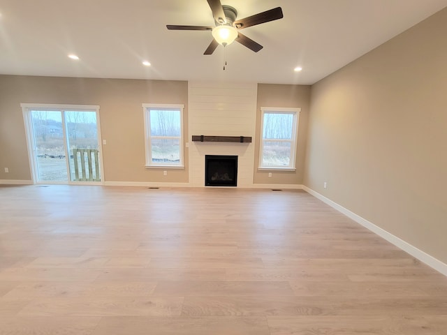 unfurnished living room featuring ceiling fan, a fireplace, and light hardwood / wood-style flooring