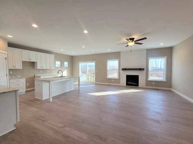 kitchen with a center island with sink, plenty of natural light, white cabinetry, and light wood-type flooring