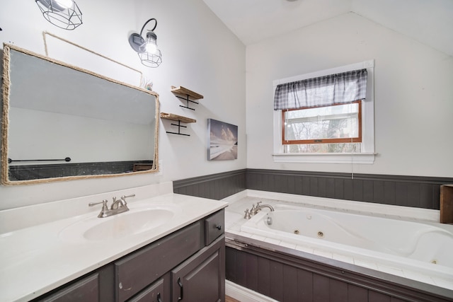 bathroom featuring vanity, a relaxing tiled tub, and vaulted ceiling