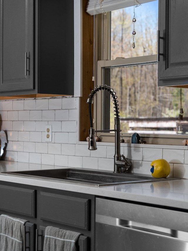 kitchen featuring tasteful backsplash, gray cabinets, and stainless steel dishwasher