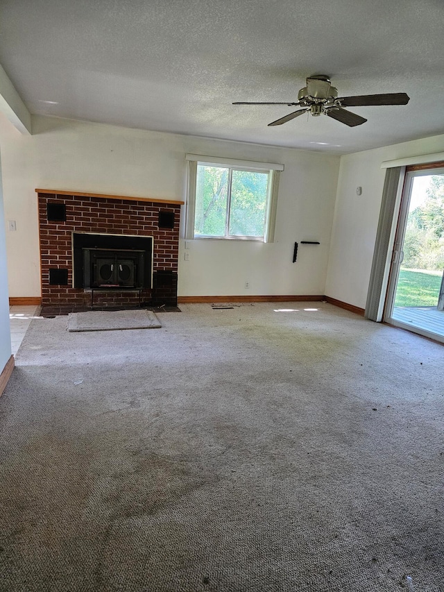 unfurnished living room with ceiling fan, light colored carpet, a healthy amount of sunlight, and a textured ceiling