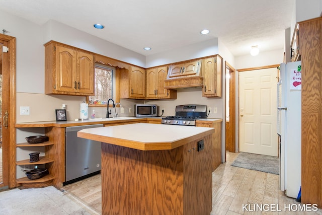 kitchen with sink, a center island, stainless steel appliances, and light wood-type flooring