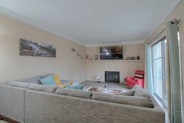 living room featuring a brick fireplace and crown molding